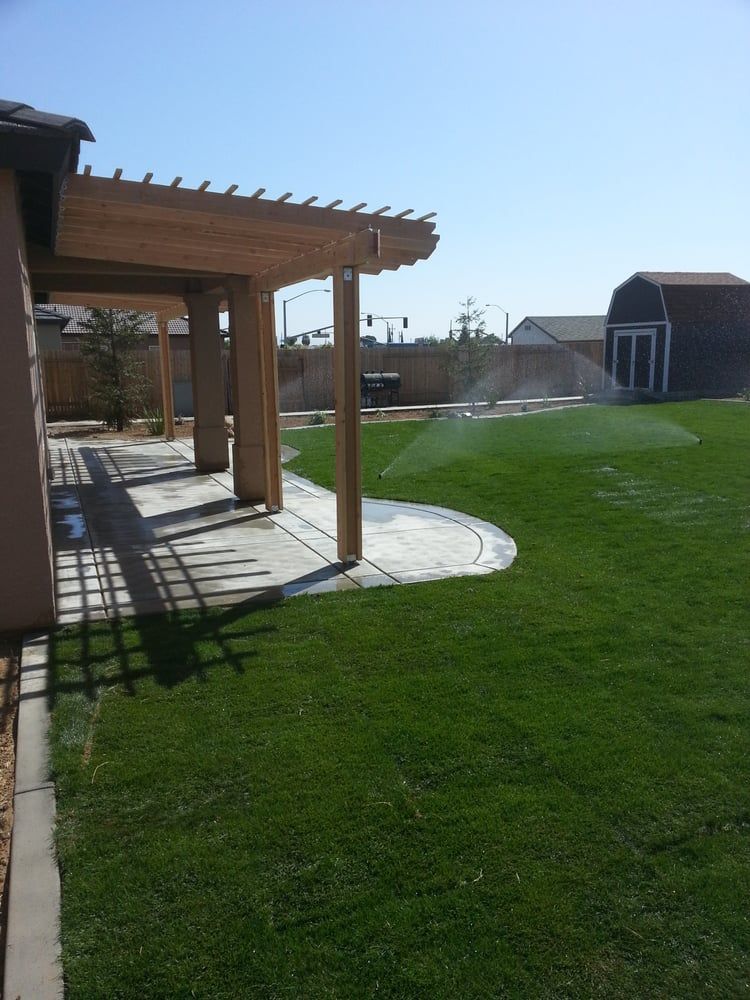 A lawn with a pergola and a barn in the background