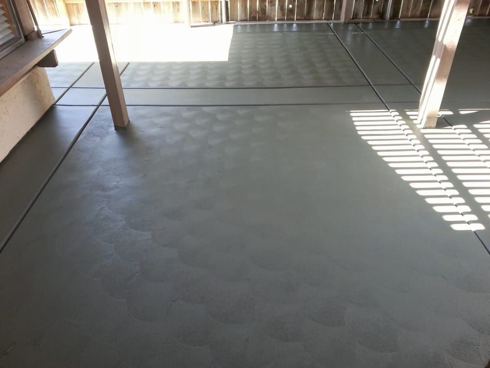 A concrete floor with a wooden fence in the background