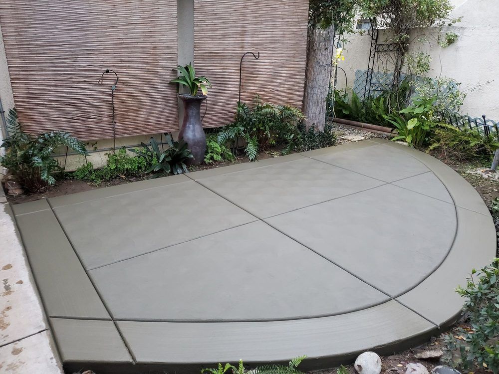 A curved concrete patio with a brick wall in the background