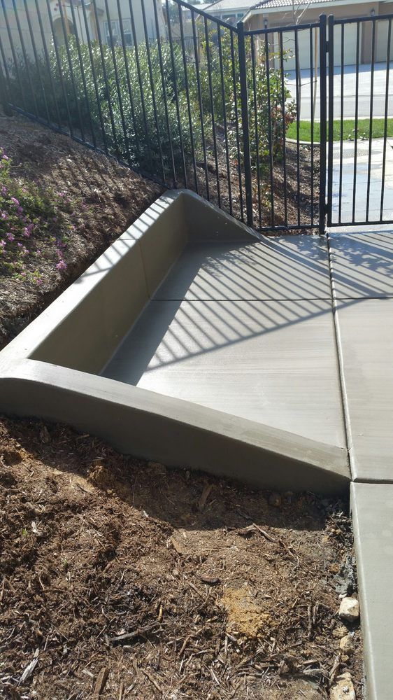 A concrete walkway is being built next to a fence.