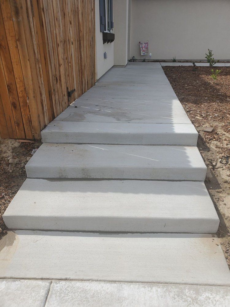 A concrete walkway with steps leading up to a house.