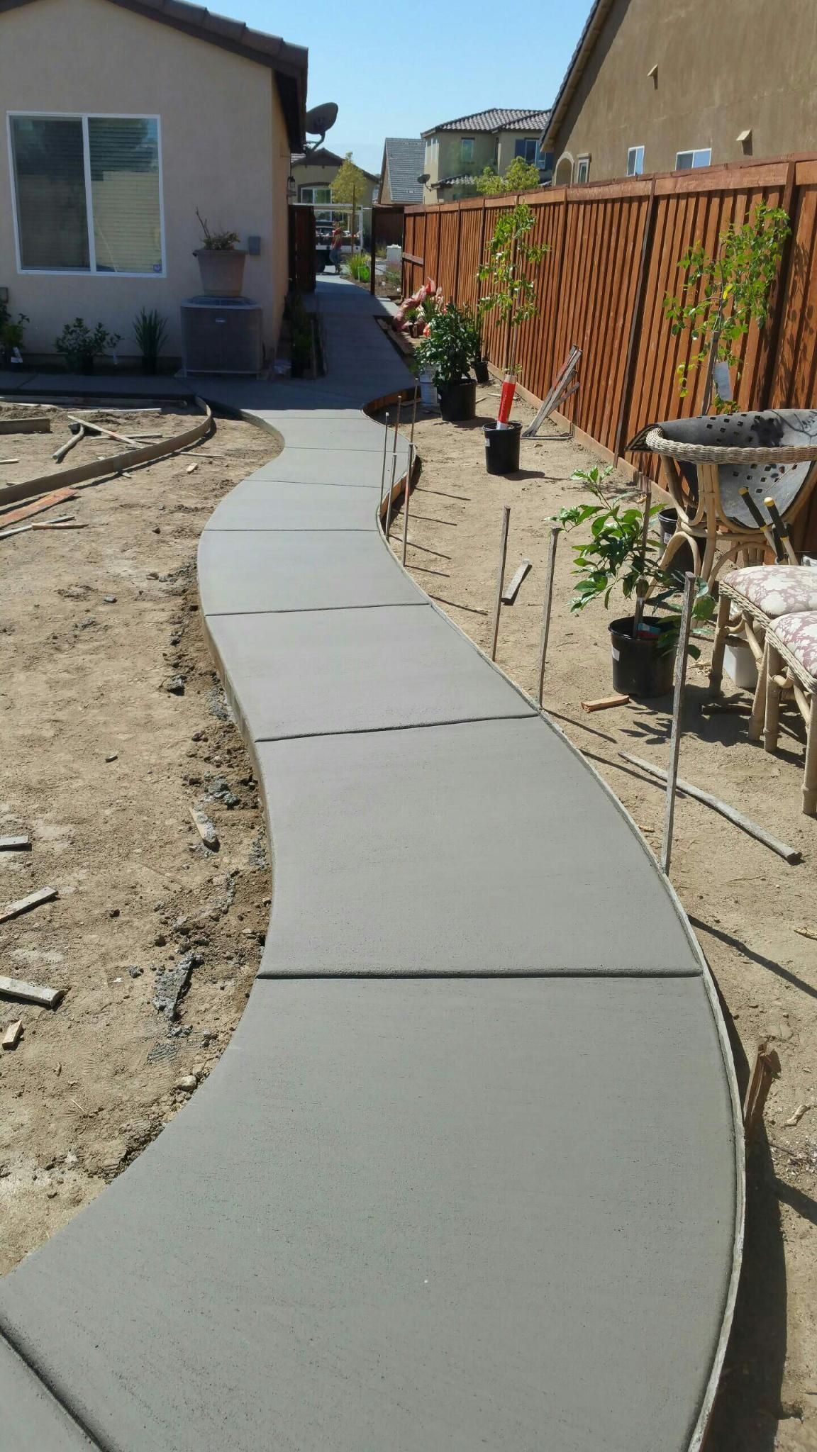 A concrete walkway is being built in front of a house