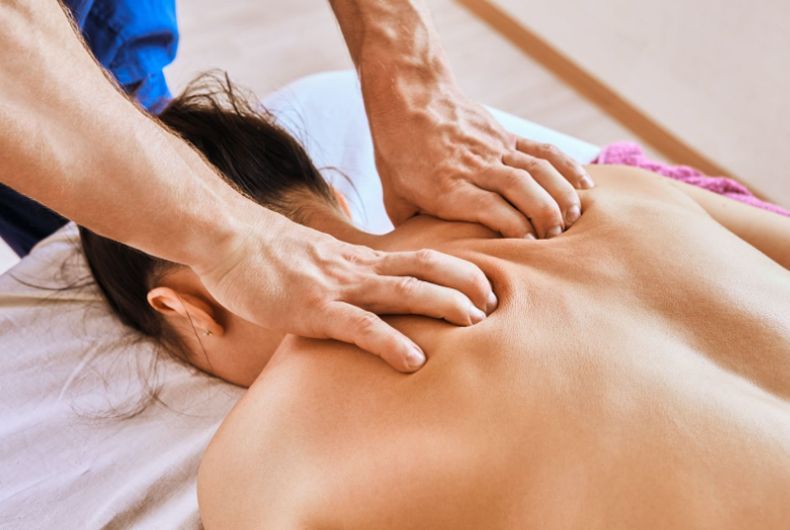 A woman is laying on a bed getting a massage from a man.