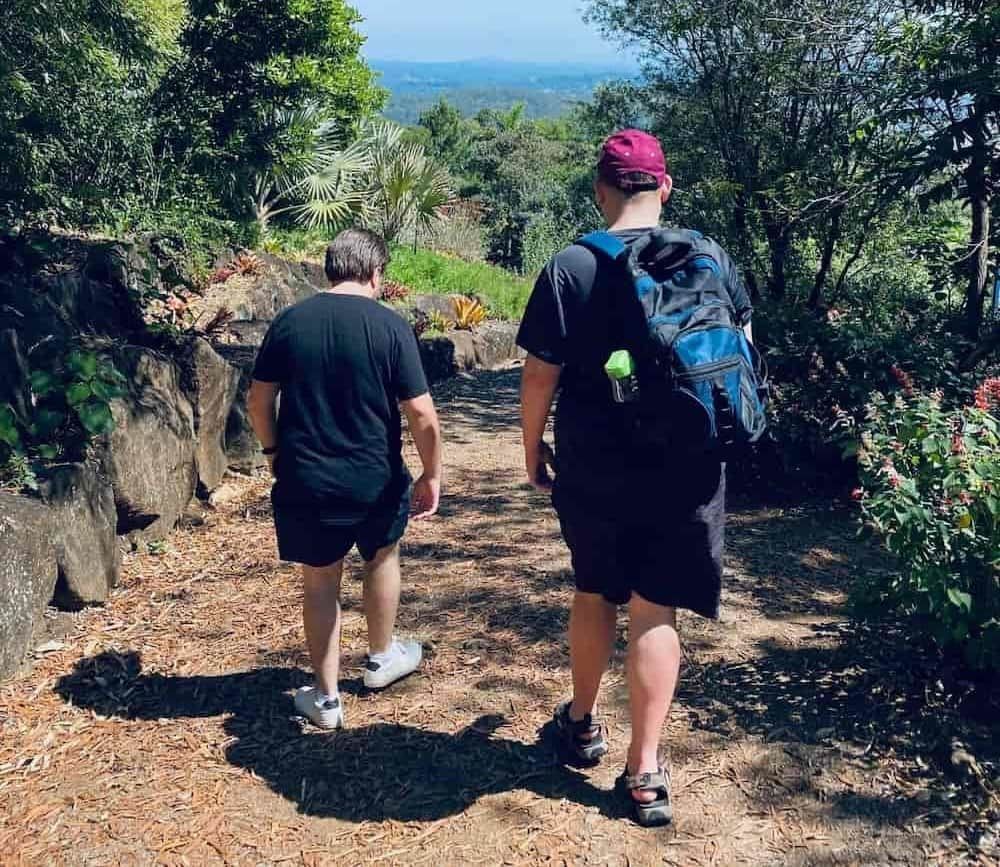 Two Men Are Walking Down A Path In The Woods — Tailored Support Services Pty Ltd In Maroochydore, QLD