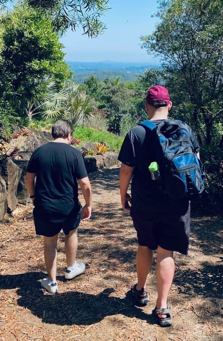 Two men are walking down a path in the woods — Tailored Support Services Pty Ltd In Maroochydore, QLD