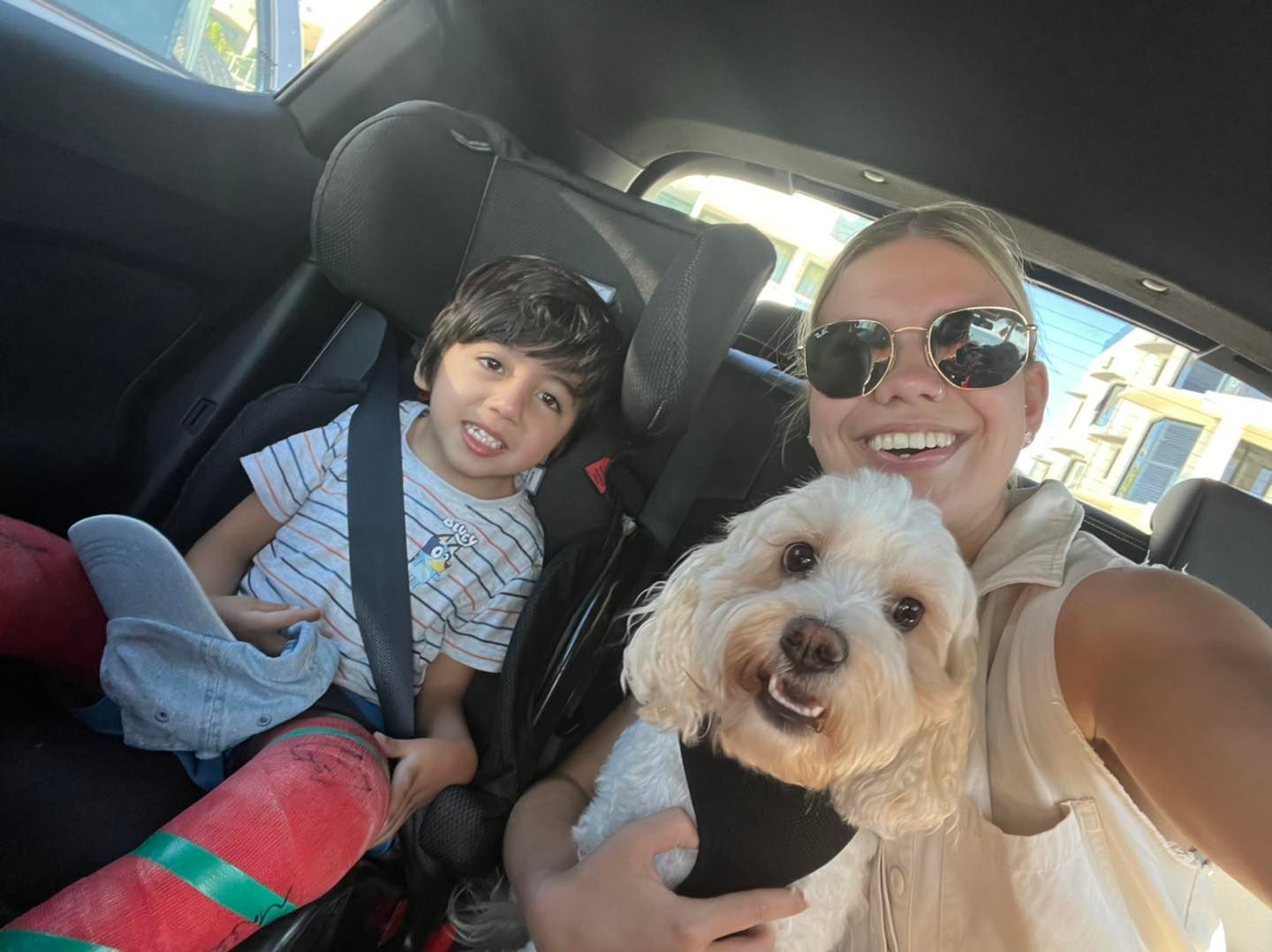 A Woman Is Sitting In A Car With A Child And A Dog — Tailored Support Services Pty Ltd In Maroochydore, QLD