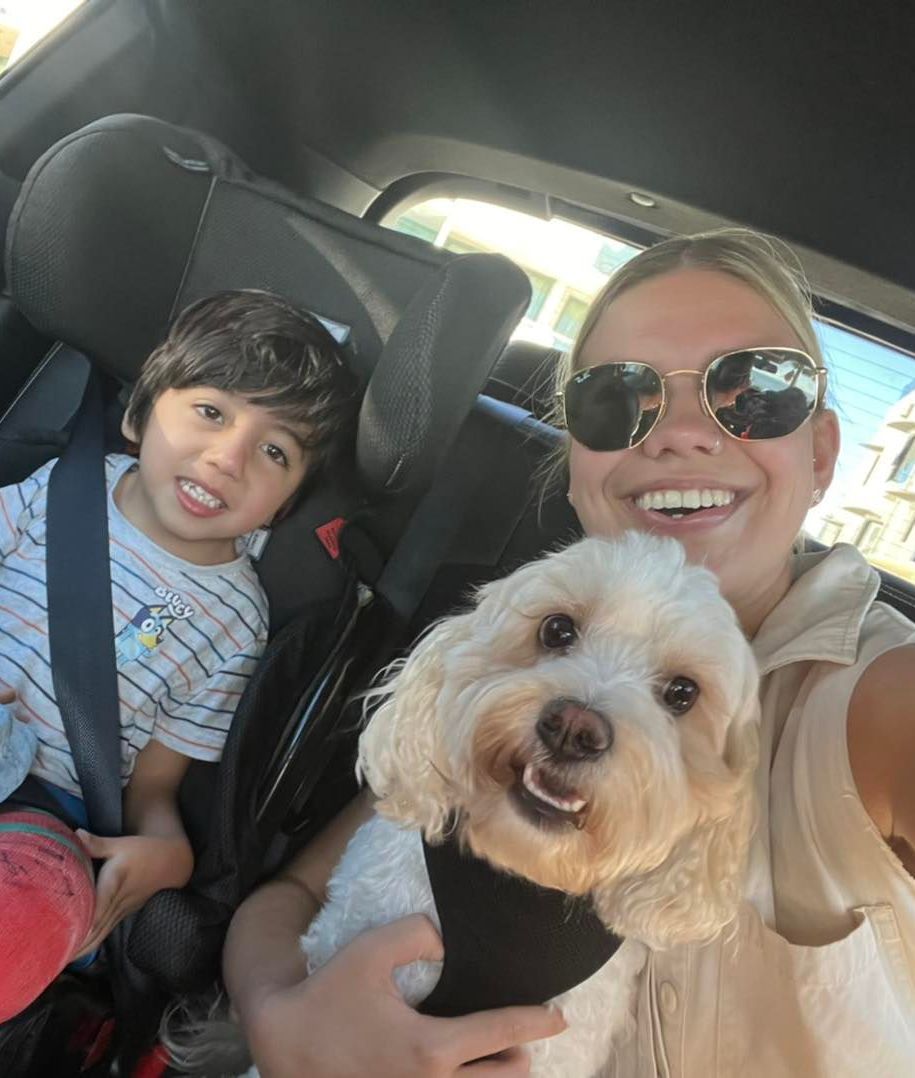 A Woman Is Taking A Selfie With A Child And A Dog In A Car Seat — Tailored Support Services Pty Ltd In Bli Bli, QLD