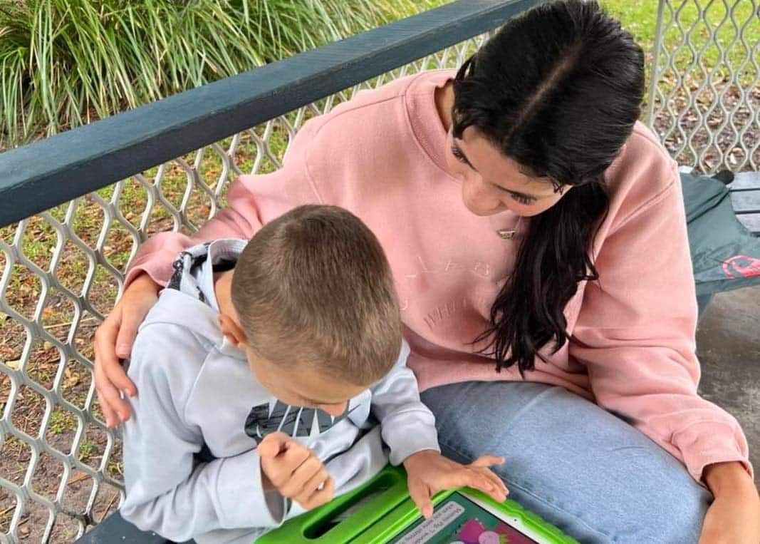 A Woman And A Child Are Sitting On A Bench Looking At A Tablet — Tailored Support Services Pty Ltd In Maroochydore, QLD
