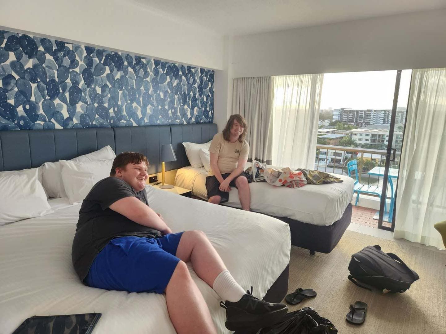 Two People Are Sitting On Beds In A Hotel Room — Tailored Support Services Pty Ltd In Maroochydore, QLD