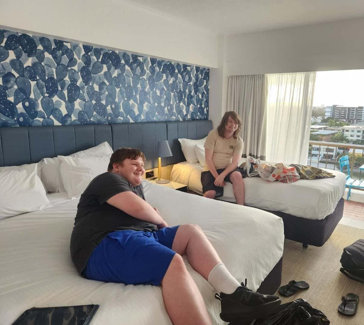 Two People Are Sitting On Beds In A Hotel Room — Tailored Support Services Pty Ltd
 In Buderim, QLD