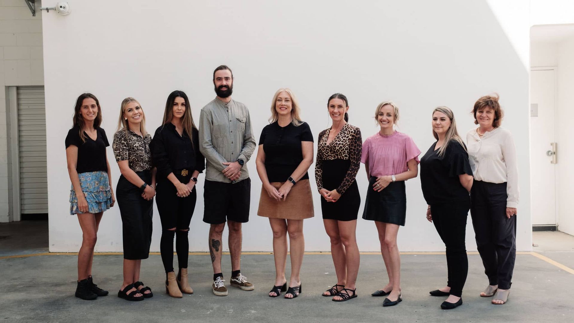 A Group Of People Standing Next To Each Other In Front Of A Wall — Tailored Support Services Pty Ltd In Maroochydore, QLD
