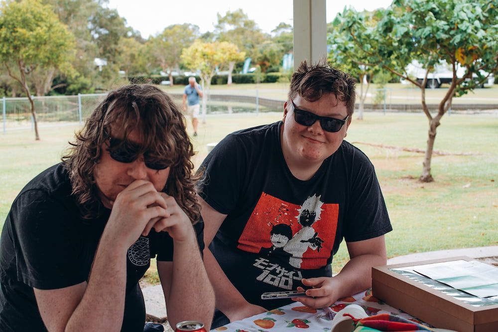 Two Men Wearing Sunglasses Are Sitting At A Table In A Park — Tailored Support Services Pty Ltd In Maroochydore, QLD