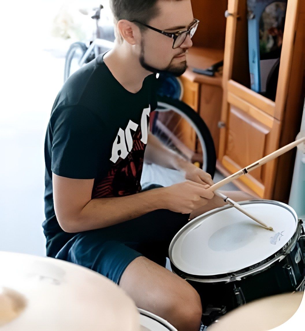 A Man Wearing A Black Shirt That Says Ac Dc Is Playing Drums — Tailored Support Services Pty Ltd In Maroochydore, QLD