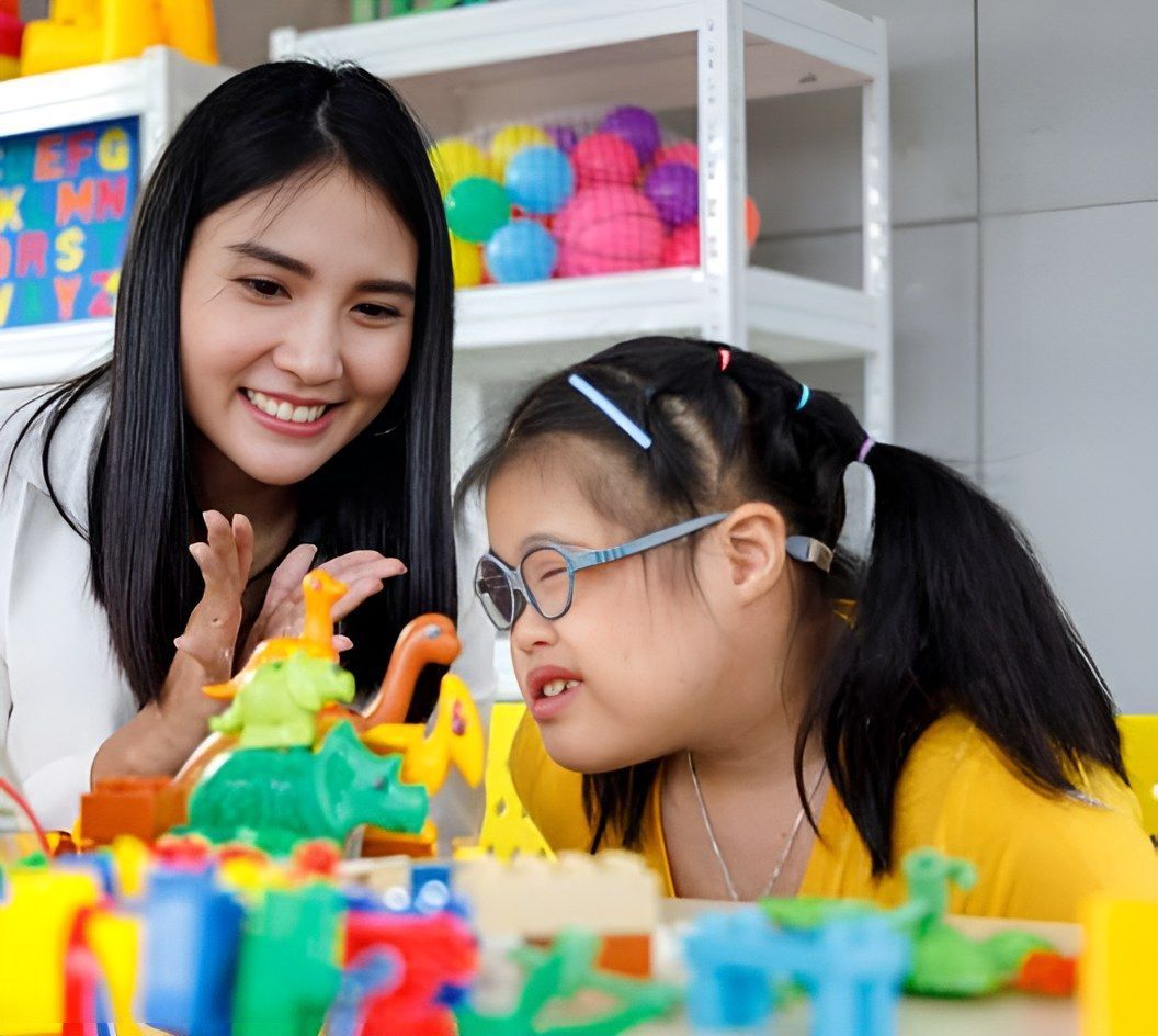 A Woman Is Teaching A Little Girl How To Play With Toys — Tailored Support Services Pty Ltd In Noosa, QLD