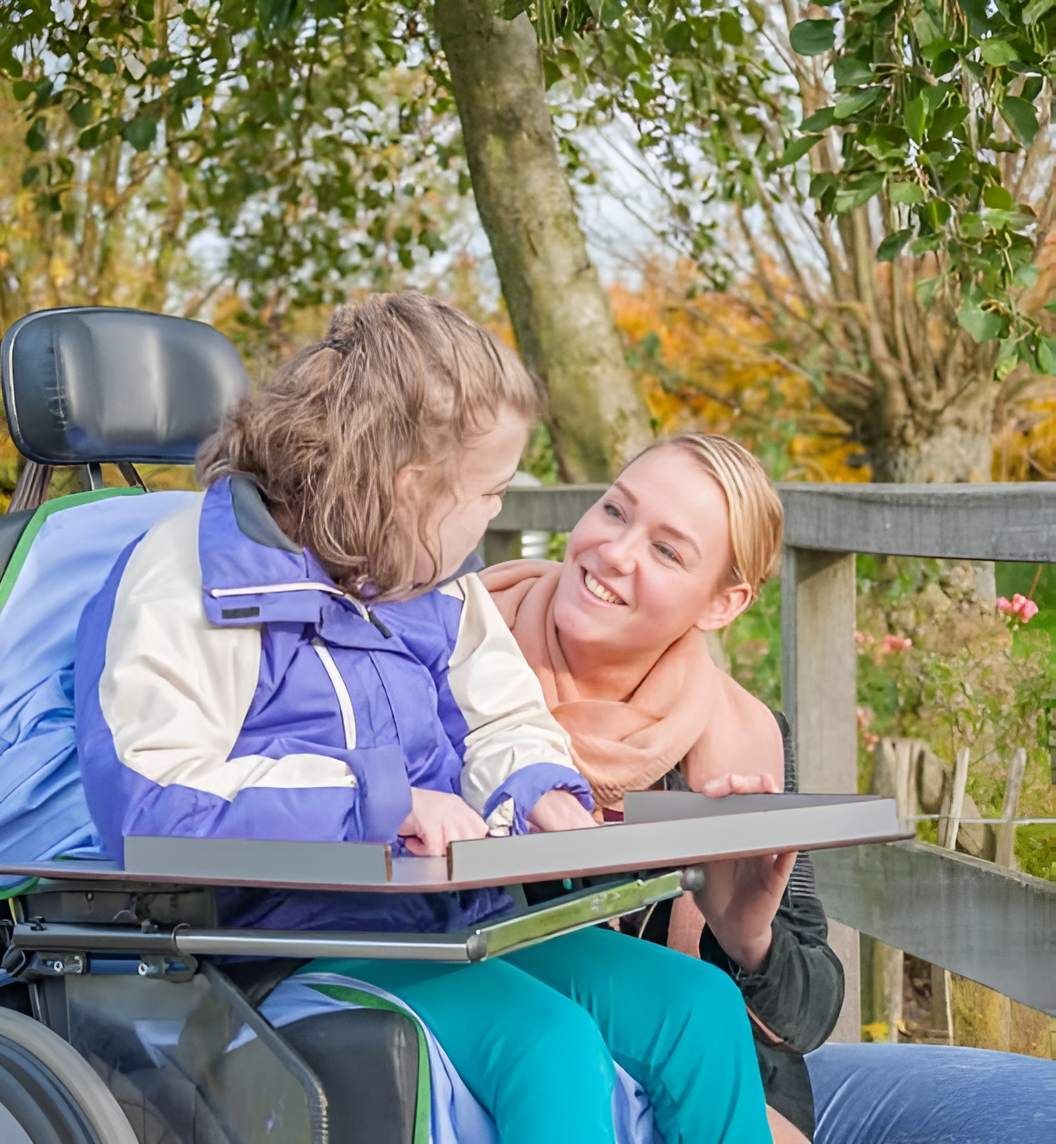 A Woman Is Sitting Next To A Young Girl In A Wheelchair — Tailored Support Services Pty Ltd
 In Buderim, QLD