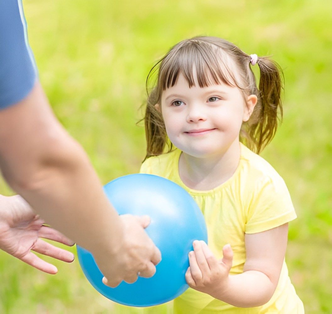 A Little Girl Is Holding A Blue Ball In Her Hands — Tailored Support Services Pty Ltd In Caloundra, QLD
