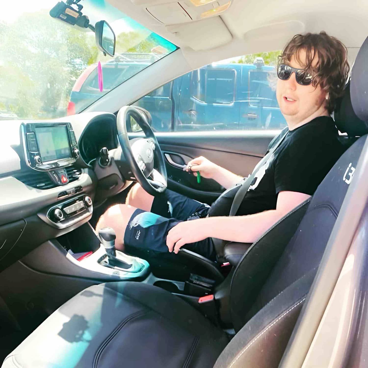 A Man Wearing Sunglasses Is Sitting In The Driver's Seat Of A Car — Tailored Support Services Pty Ltd
 In Buderim, QLD