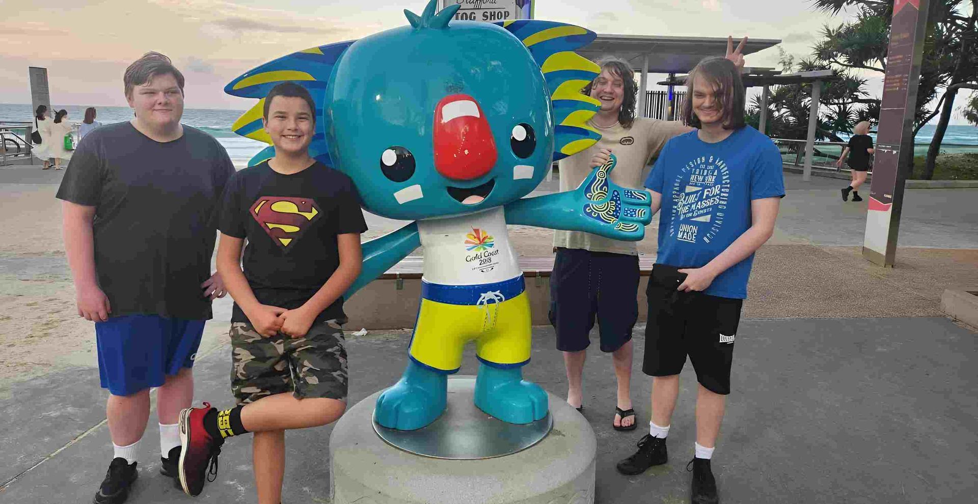 A Group Of Young Men Are Standing Next To A Statue Of A Koala — Tailored Support Services Pty Ltd In Maroochydore, QLD