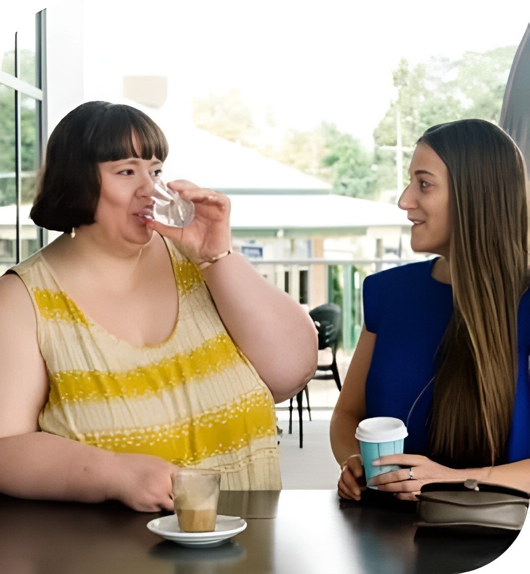 Two Women Are Sitting At A Table Drinking Coffee — Tailored Support Services Pty Ltd In Maroochydore, QLD