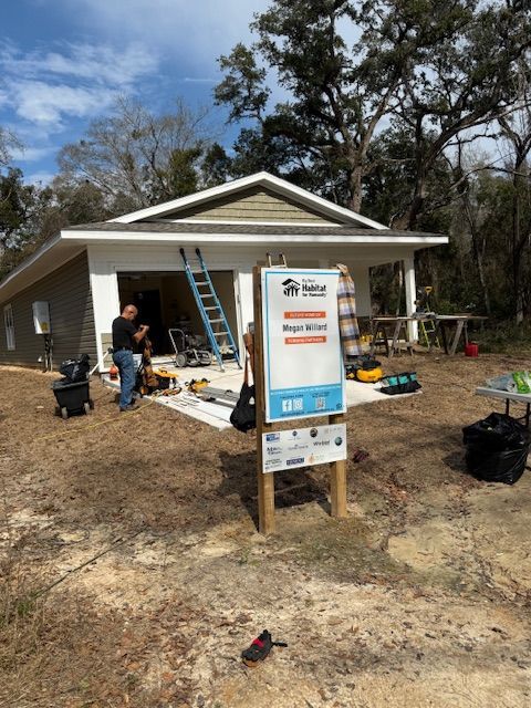 Sign in front of a house under construction; man working.
