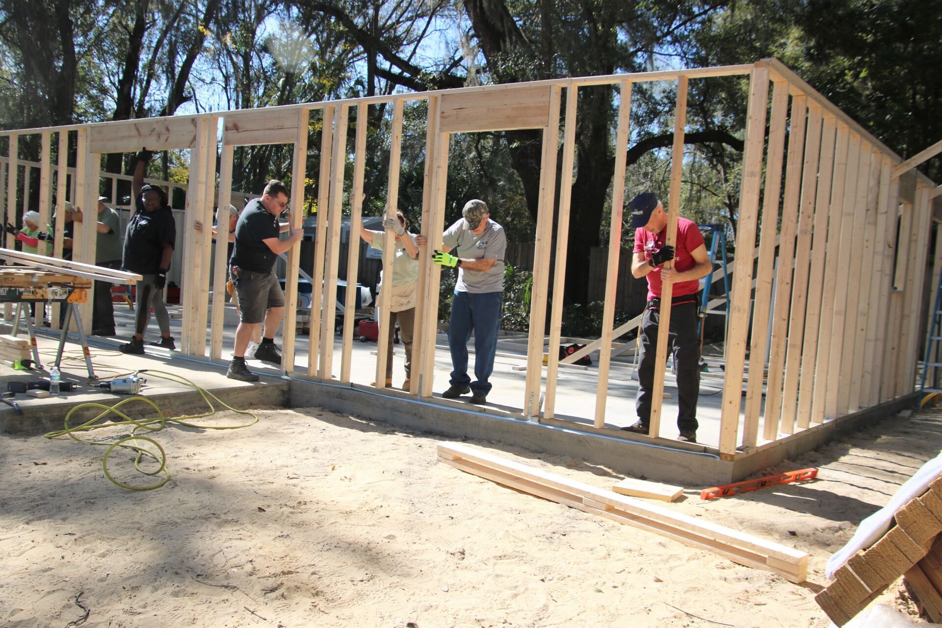 People framing a wood-stud structure outdoors, likely for a building.