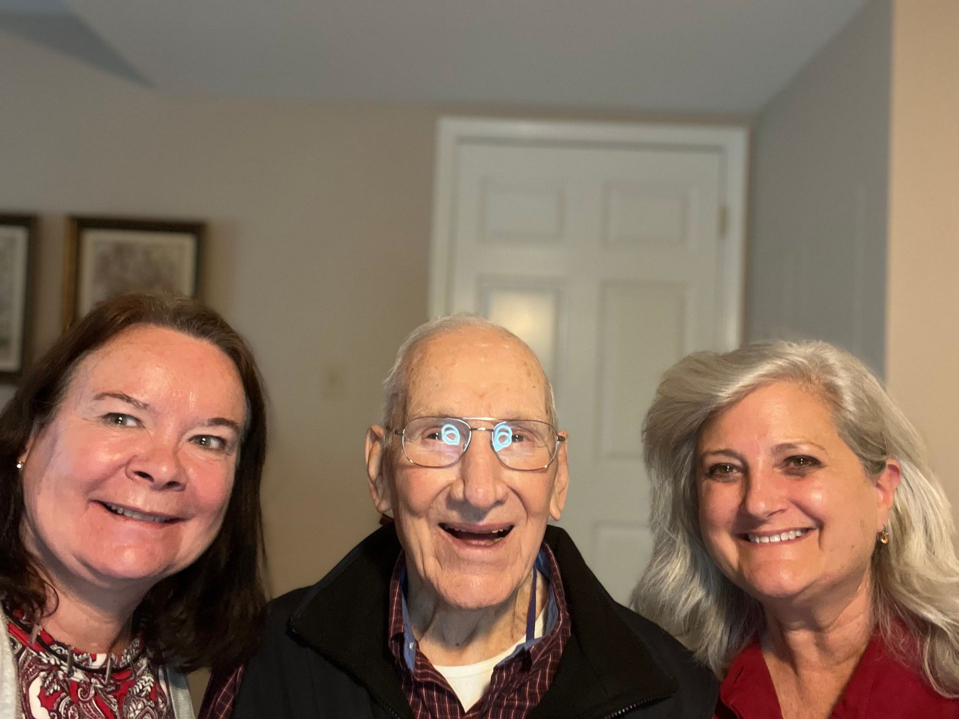 Two women and an older man are posing for a picture