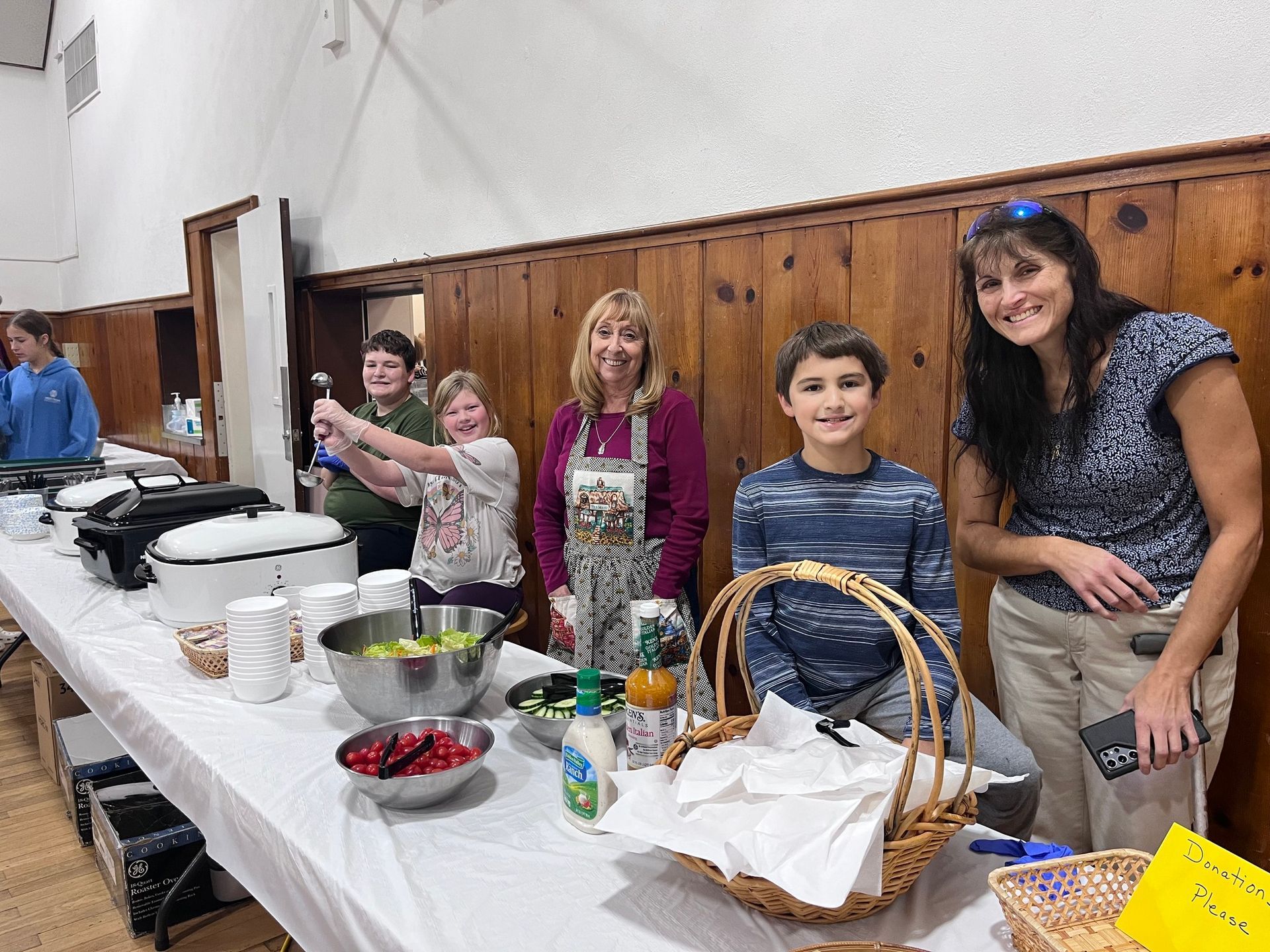 A group of people standing around a table with bowls and baskets