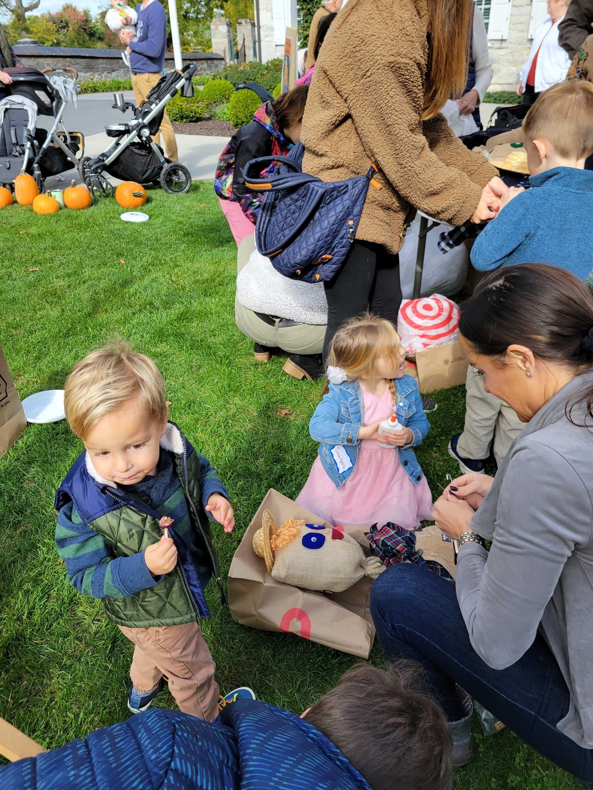 Children at an outdoor event, pumpkins in the background, two children near a Target bag.