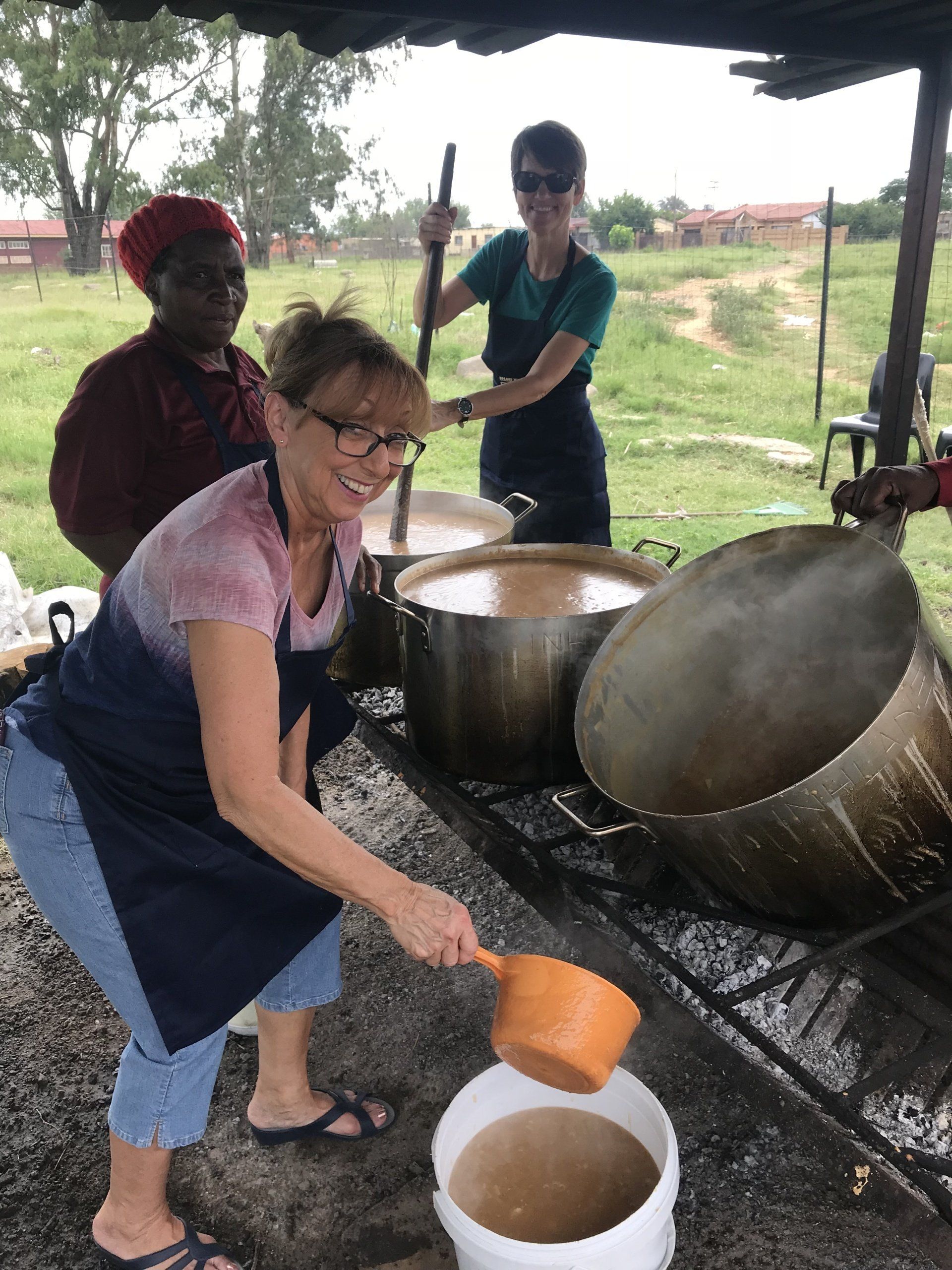 A woman is pouring liquid into a white bucket