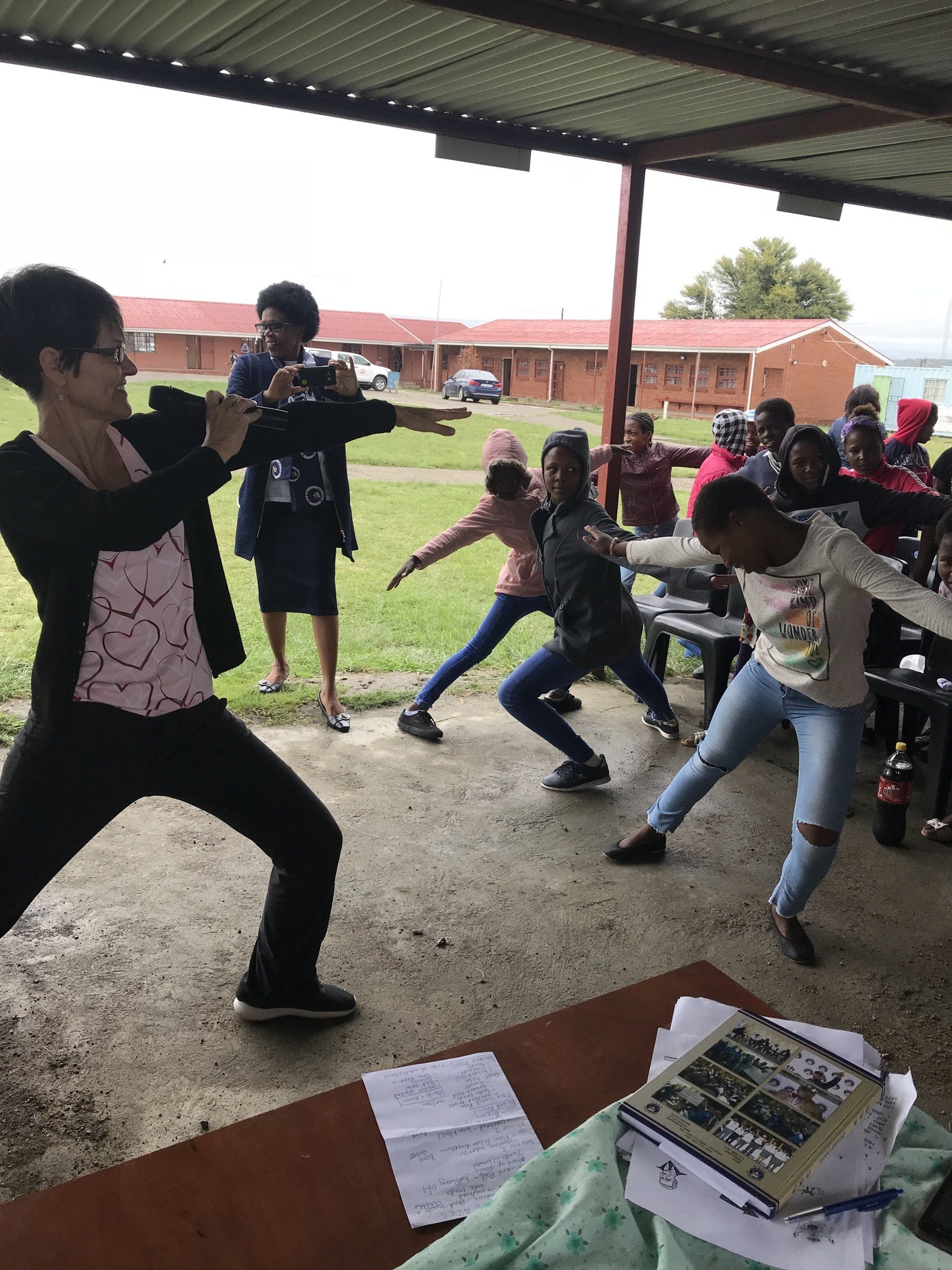 A woman in a pink shirt is standing in front of a group of children