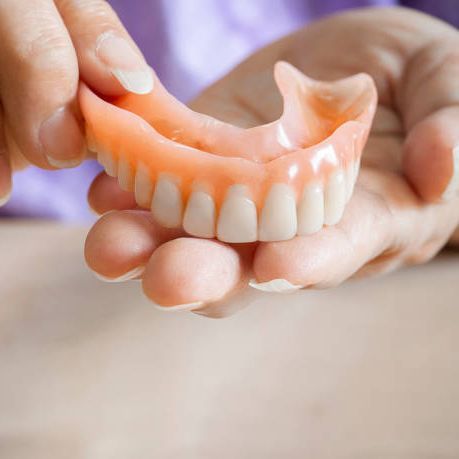 A person is holding a denture in their hands.