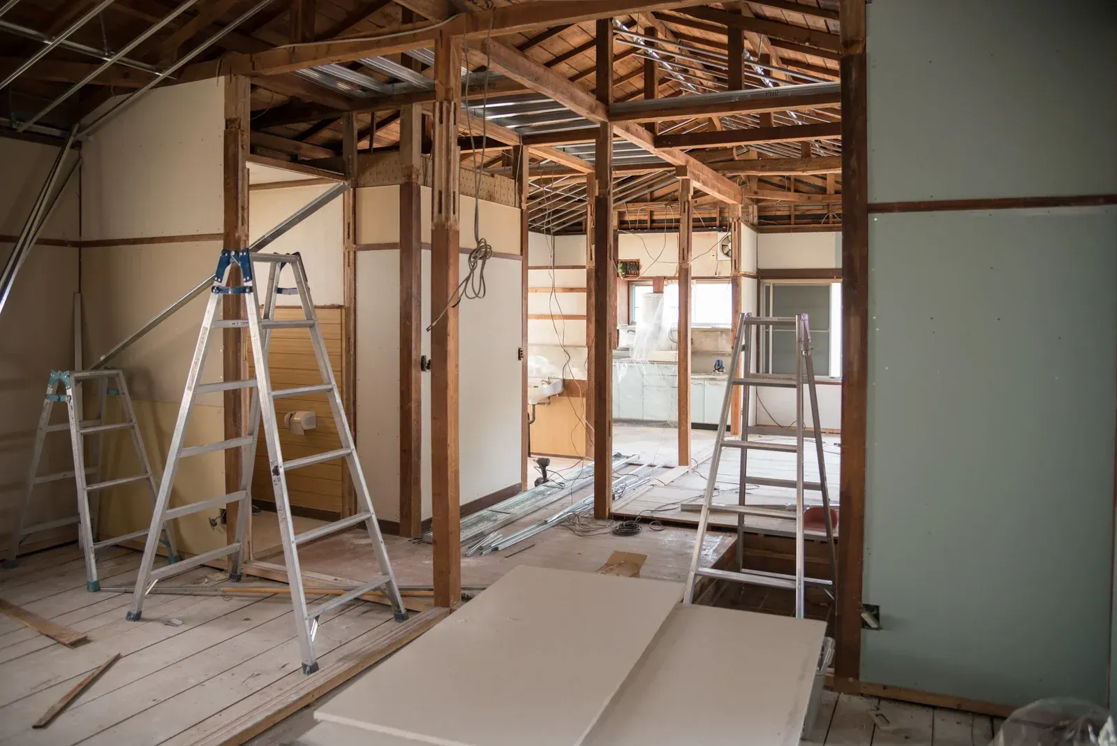 Interior renovation with exposed wooden beams, ladders, and construction materials.