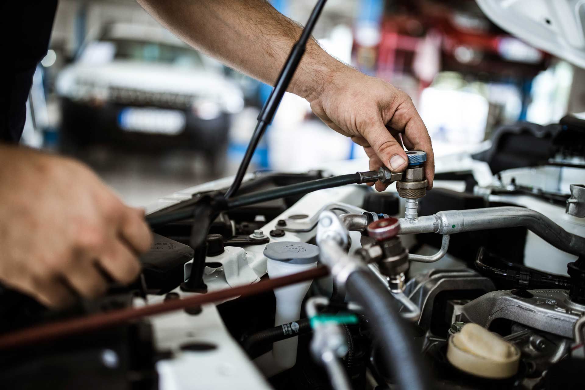 A man is working on the engine of a car in a garage.