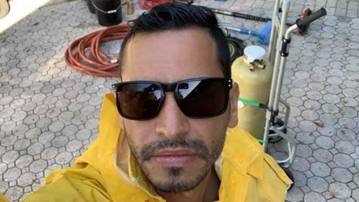 A man wearing sunglasses and a yellow jacket is taking a selfie