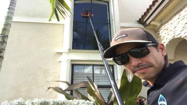 A man wearing sunglasses and a hat is cleaning a window