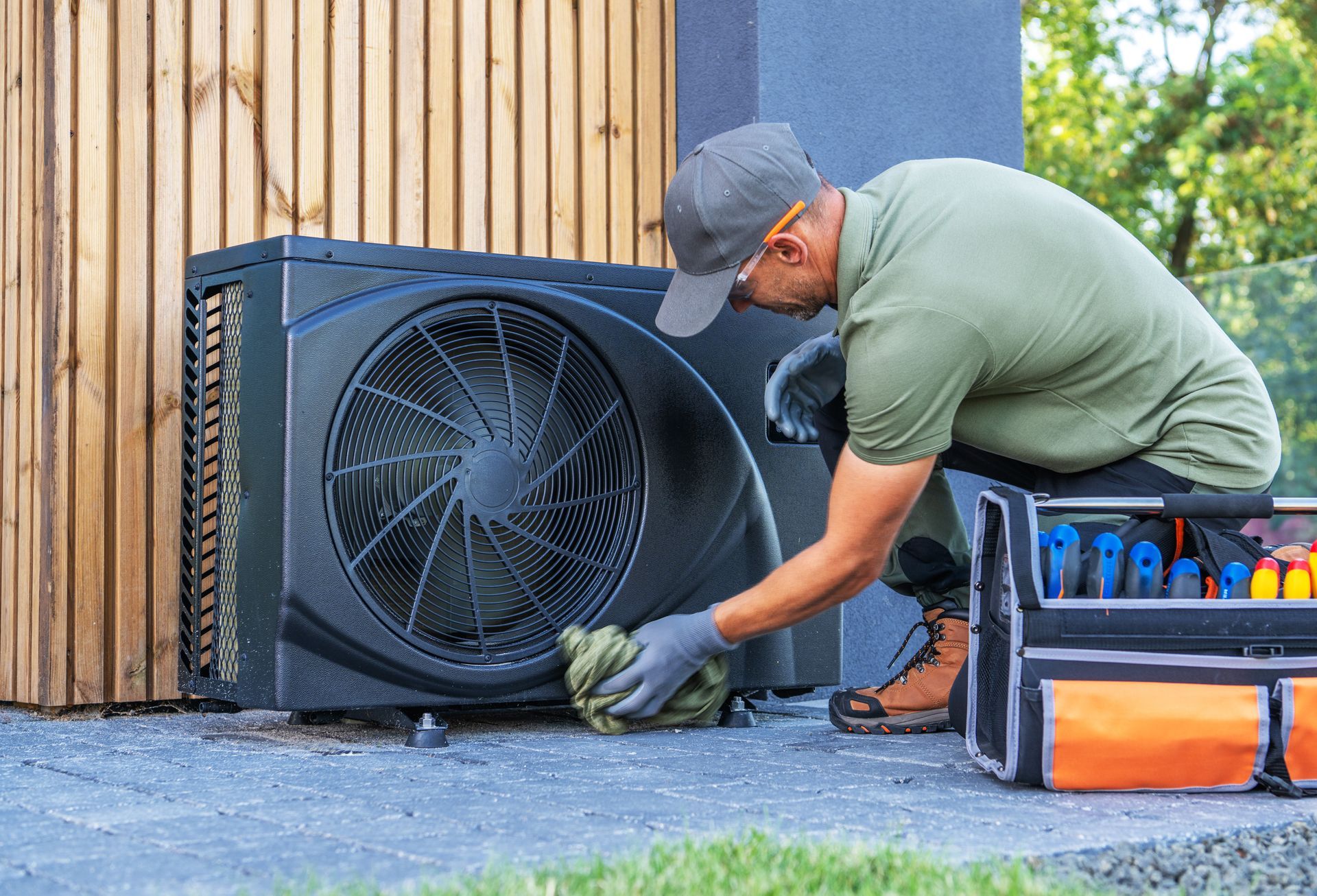 HVAC technician inspecting a heat pump outdoors, tools visible.