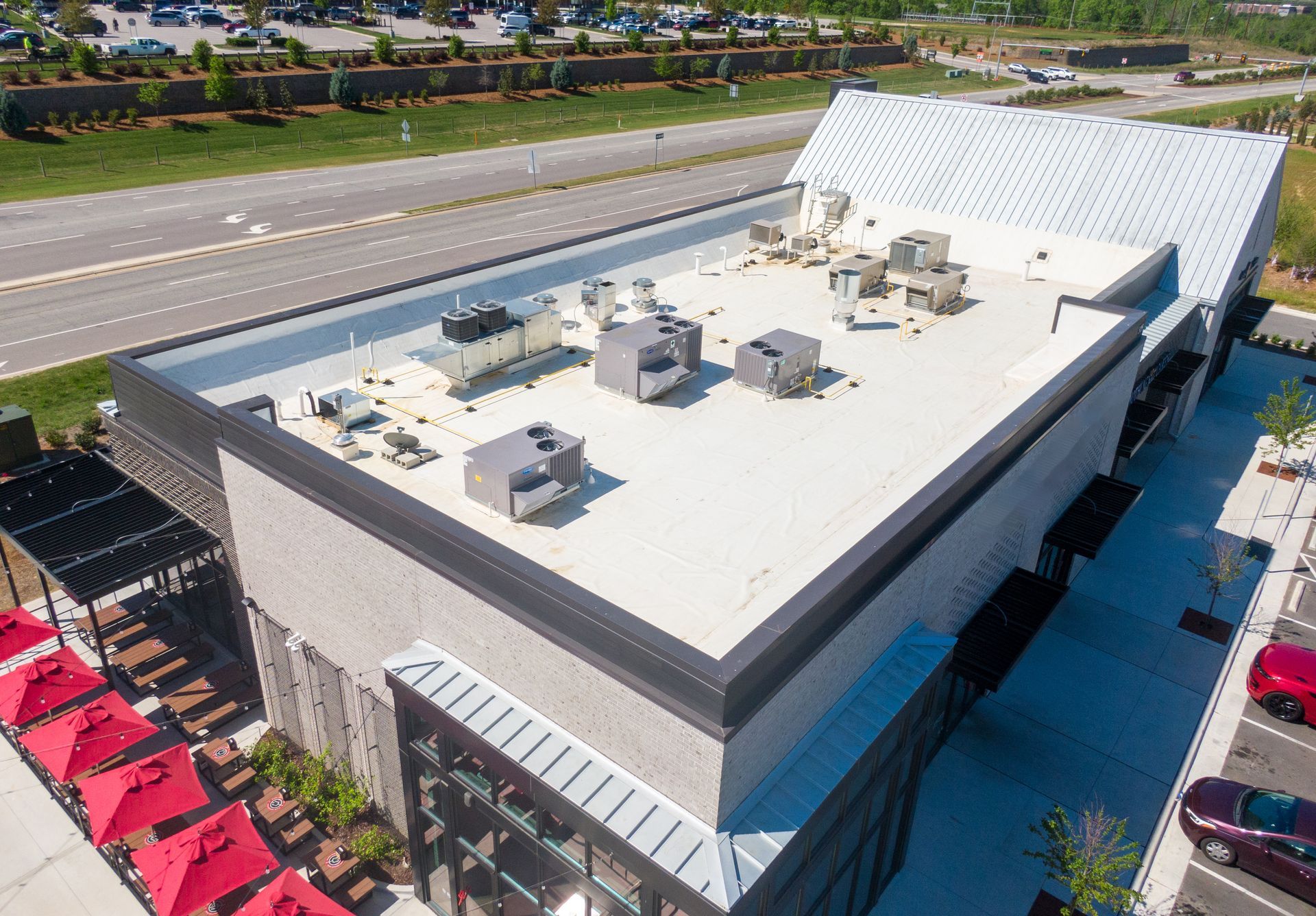 Aerial view of a commercial building with a white metal roof and multiple HVAC units.