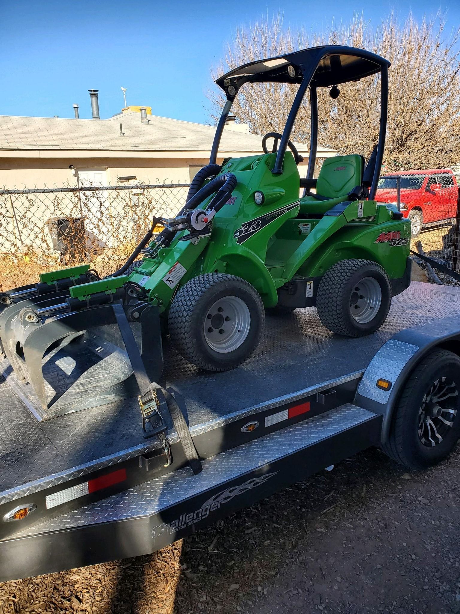 A green tractor is sitting on top of a trailer.