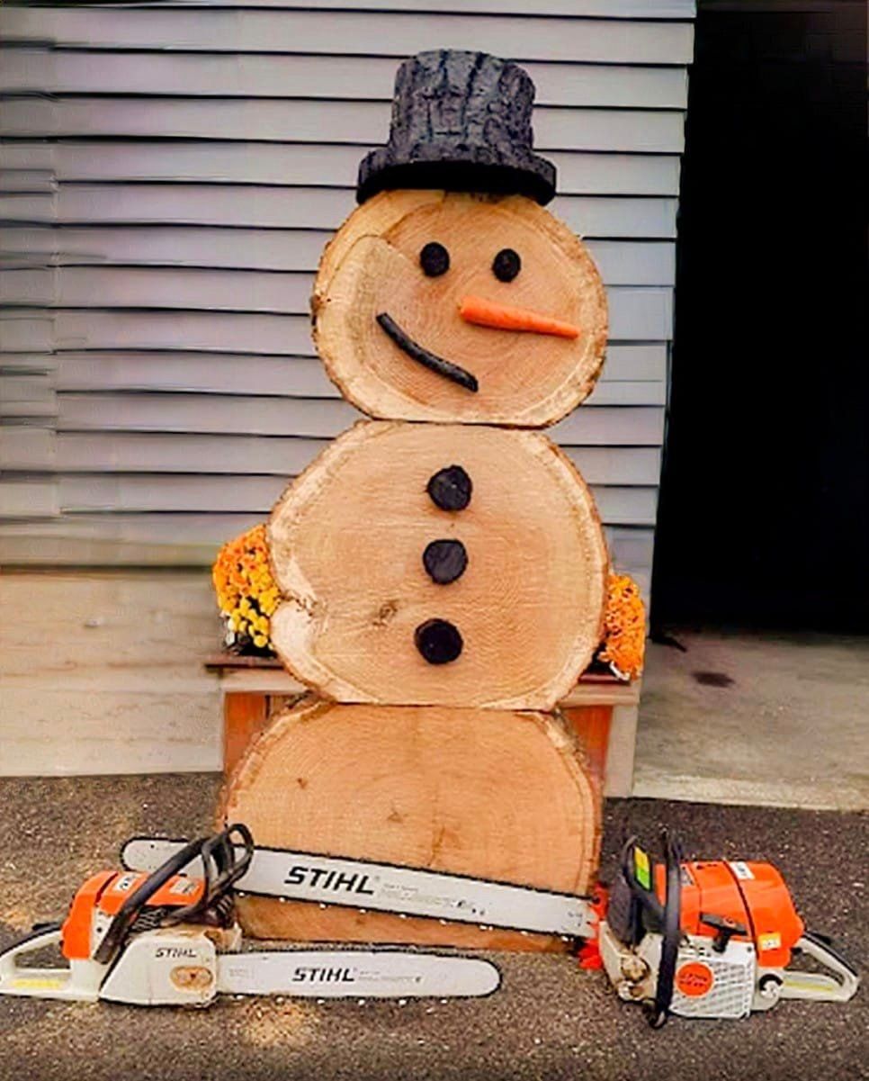 A snowman made out of logs and chainsaws.