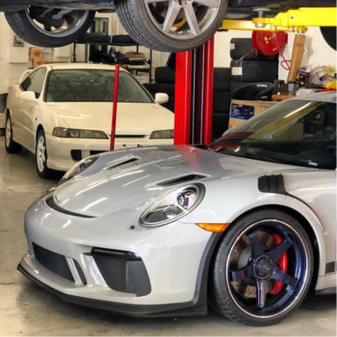 Silver Porsche sports car and white Acura Integra in a garage. | The Garage