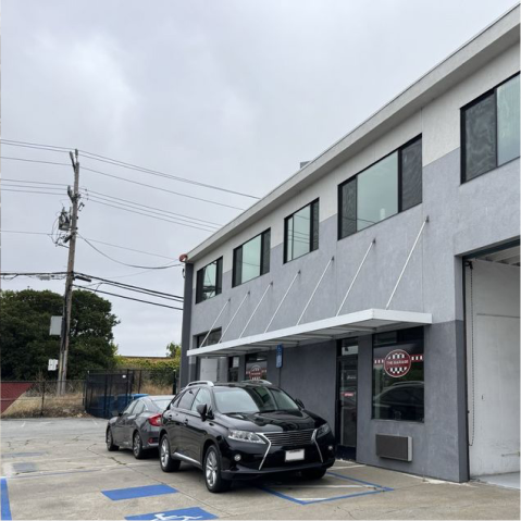 Two-story building with awning, cars parked in front. | The Garage