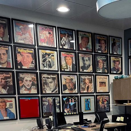 Collection of framed magazine covers as wall art above a corner desk