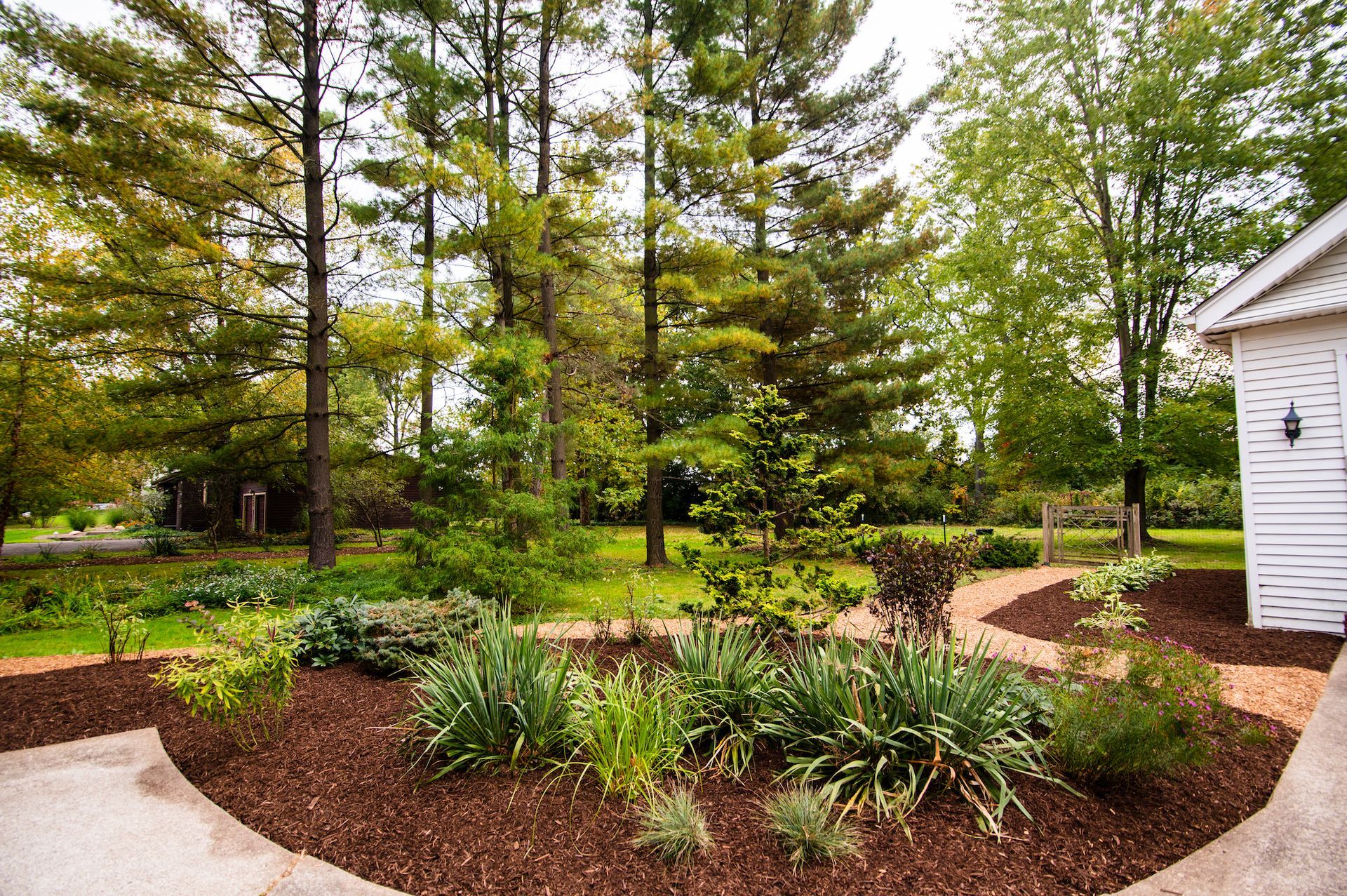 A white house is surrounded by trees and a garden.