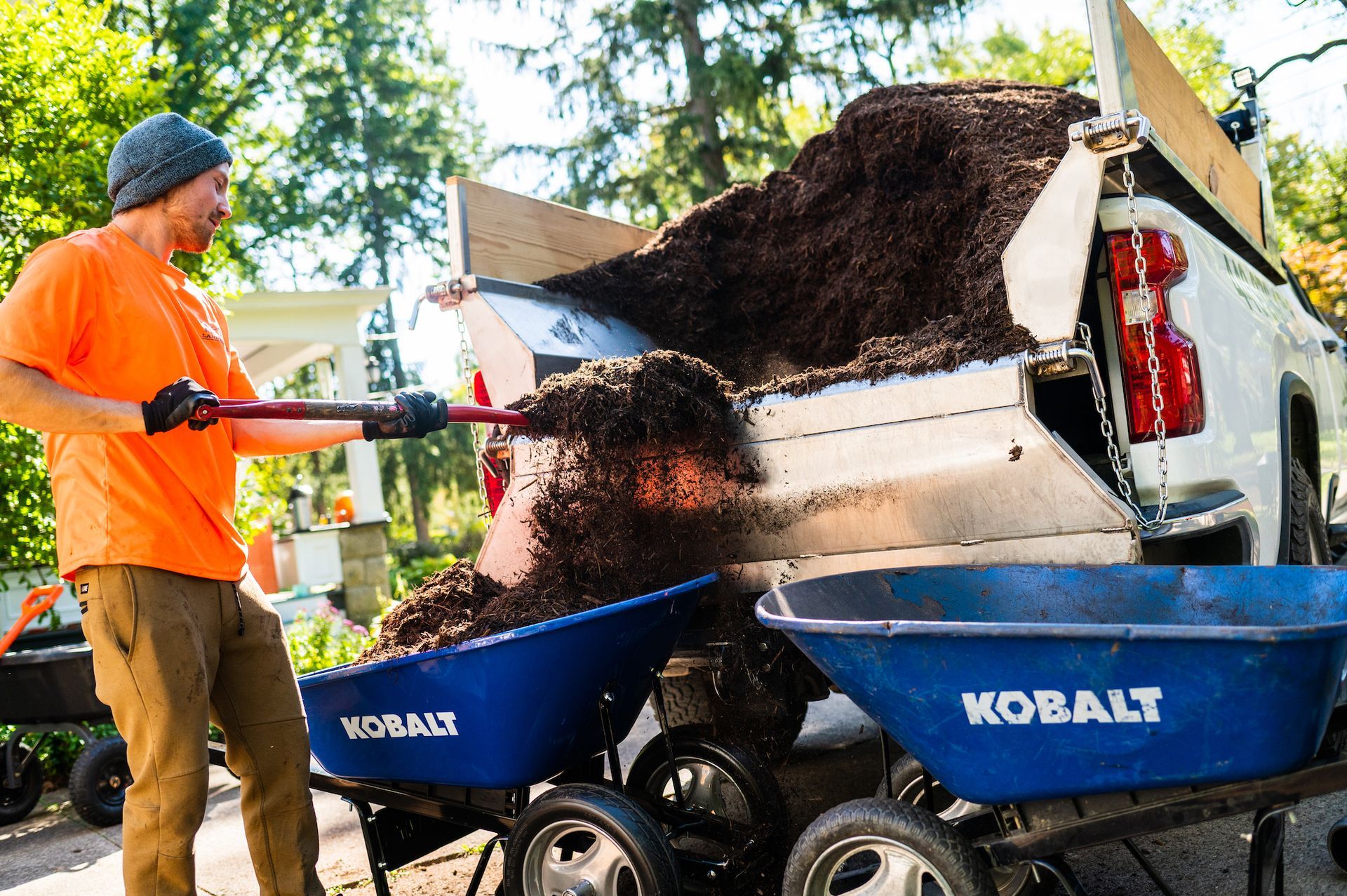 A man is pushing a wheelbarrow full of dirt into a truck.