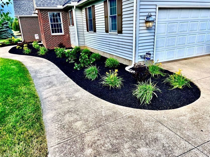 A walkway leading to a house with a lush green lawn and a garage door.