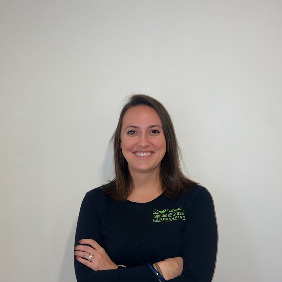 A woman in a black shirt is smiling with her arms crossed.