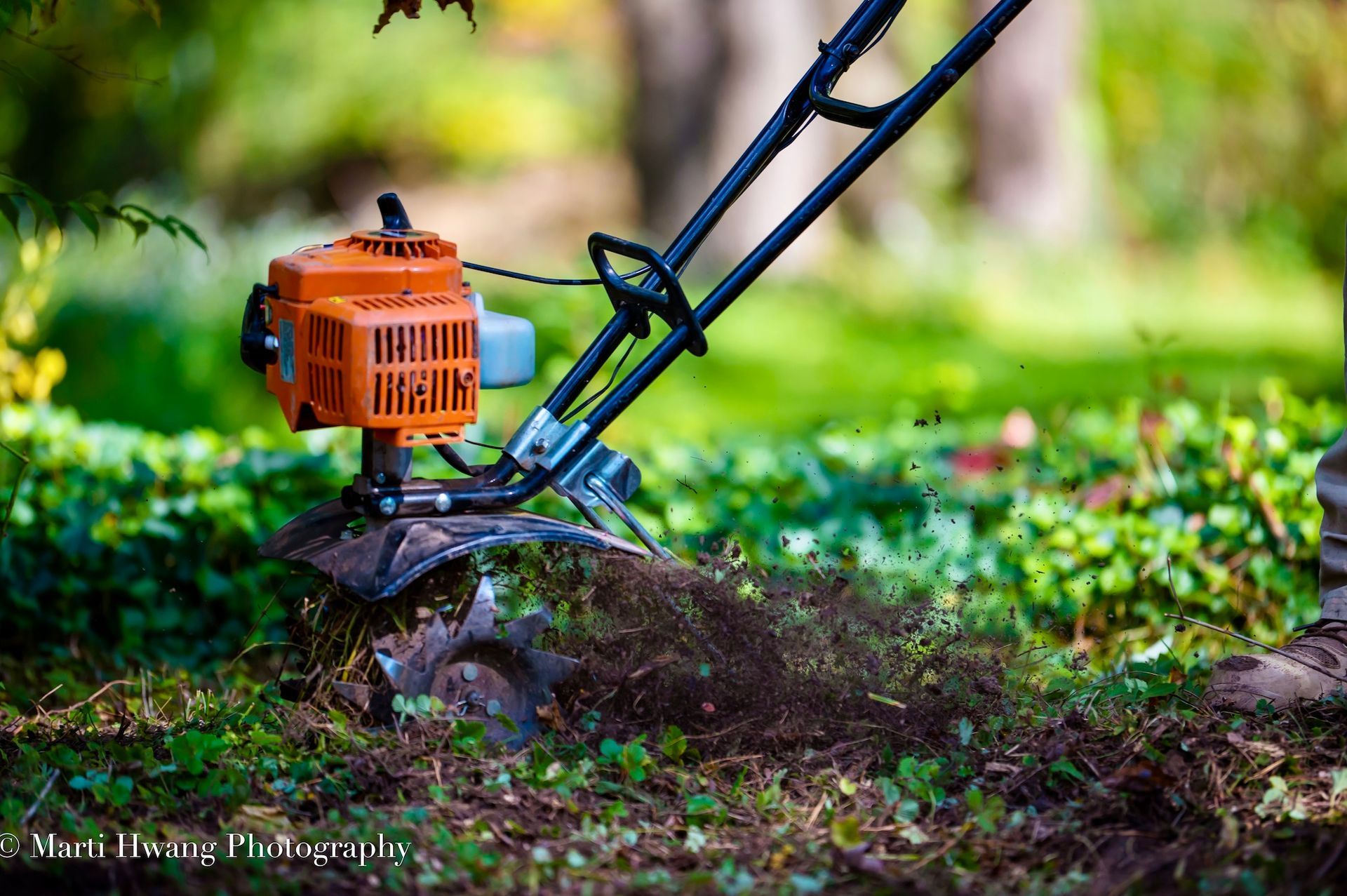A small orange lawn mower is sitting on top of a pile of dirt.