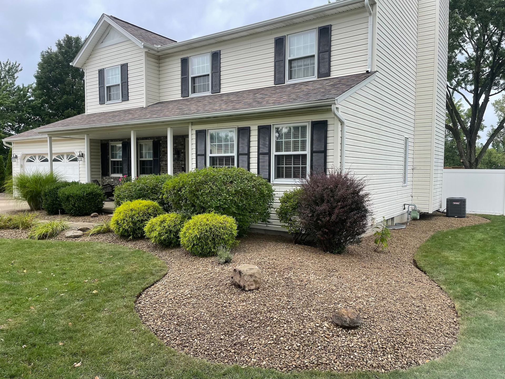 A large white house with black shutters and a large lawn in front of it.