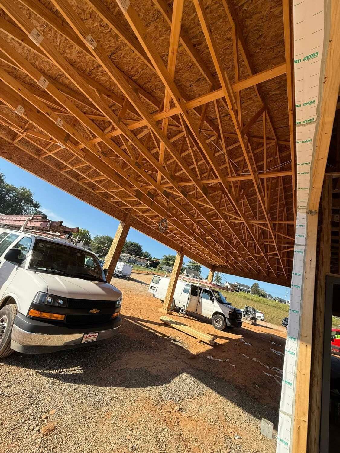 Construction site with wood framing, vans parked below.