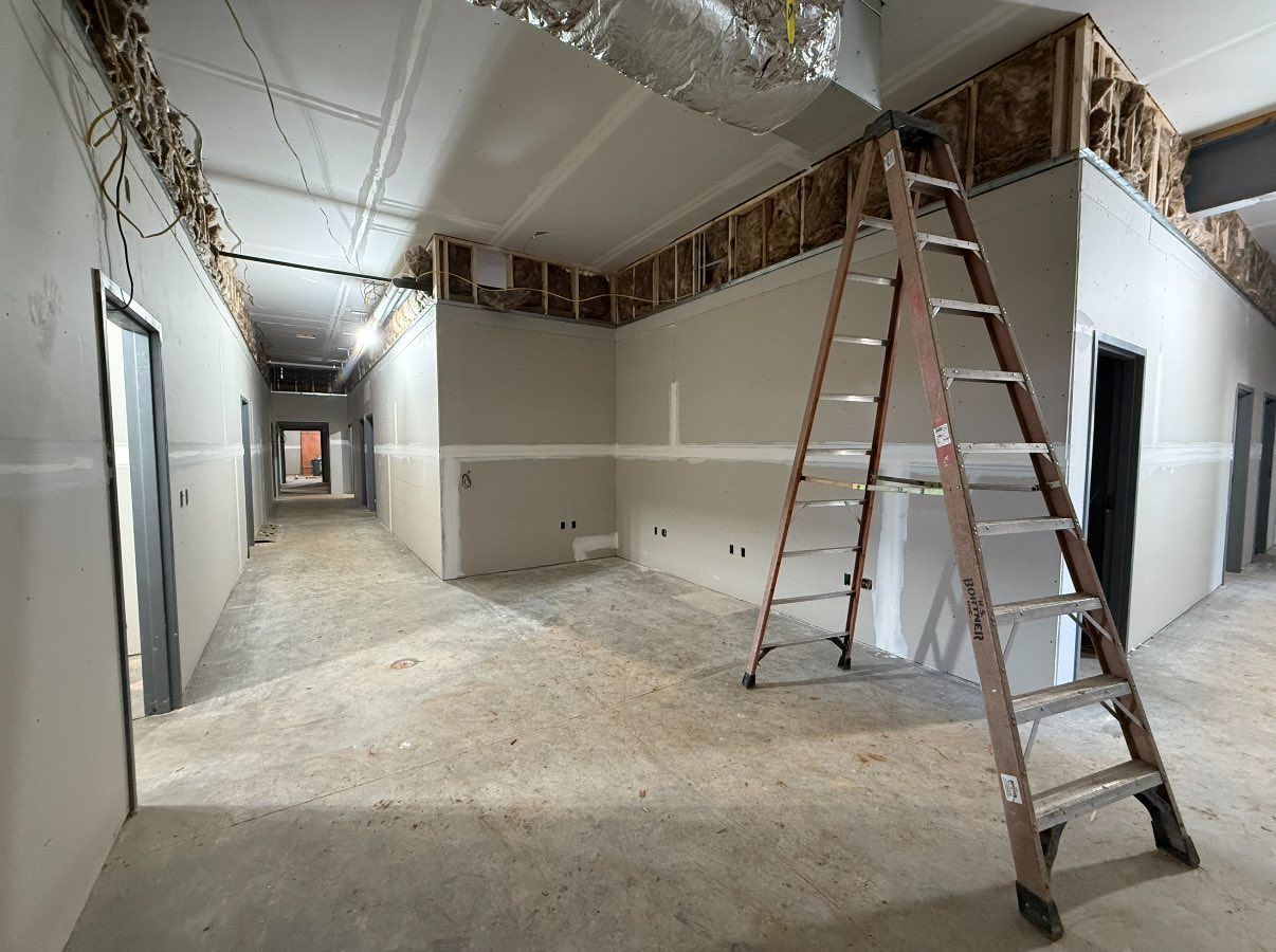 Hallway under construction with a ladder leaning against a wall. Unfinished drywall.